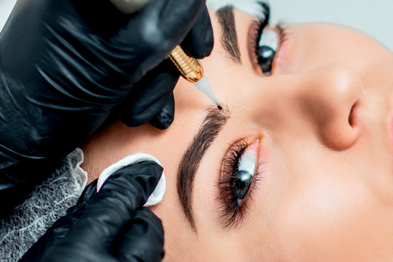 Microblading artist using a dermograph or tebori to create microbladed eyebrows on a woman