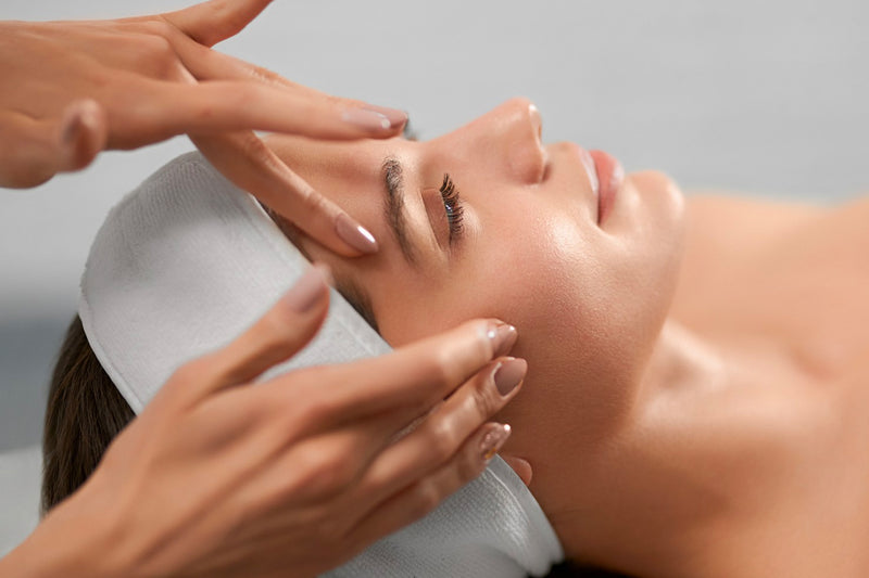  A woman receiving a lymphatic face drainage massage to detox her face, eliminate excess of fluid and keep the skin healthy