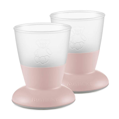 Two Babybjorn baby cups in powder pink, featuring a teddy bear design and a sturdy base for easy handling.