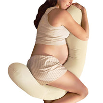 Pregnant woman in a sleeveless top and striped shorts cuddling an ivory Frida Mom 4-in-1 Cooling Pregnancy Pillow.