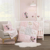 Disney Minnie Mouse crib bedding set in pink tones, featuring a quilt with Minnie graphics, decorative pillow, and wall art.