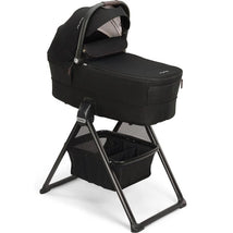 NUNA MIXX Series bassinet in caviar/chocolate color, featuring a sturdy stand and storage basket below.