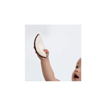 Cheerful baby holding a chewable toy shaped like a coconut, showcasing its textured brown edge and smooth interior.