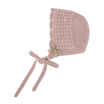 Knit newborn bonnet in powder pink and light brown, featuring a decorative flower and tie straps.