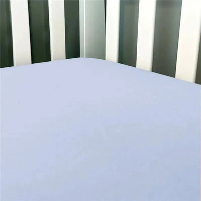 Solid blue flannel crib sheet draped over a crib mattress, with white crib slats visible in the background.