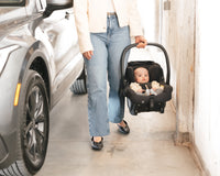 Mom carrying baby in car seat near SUV for safe travel