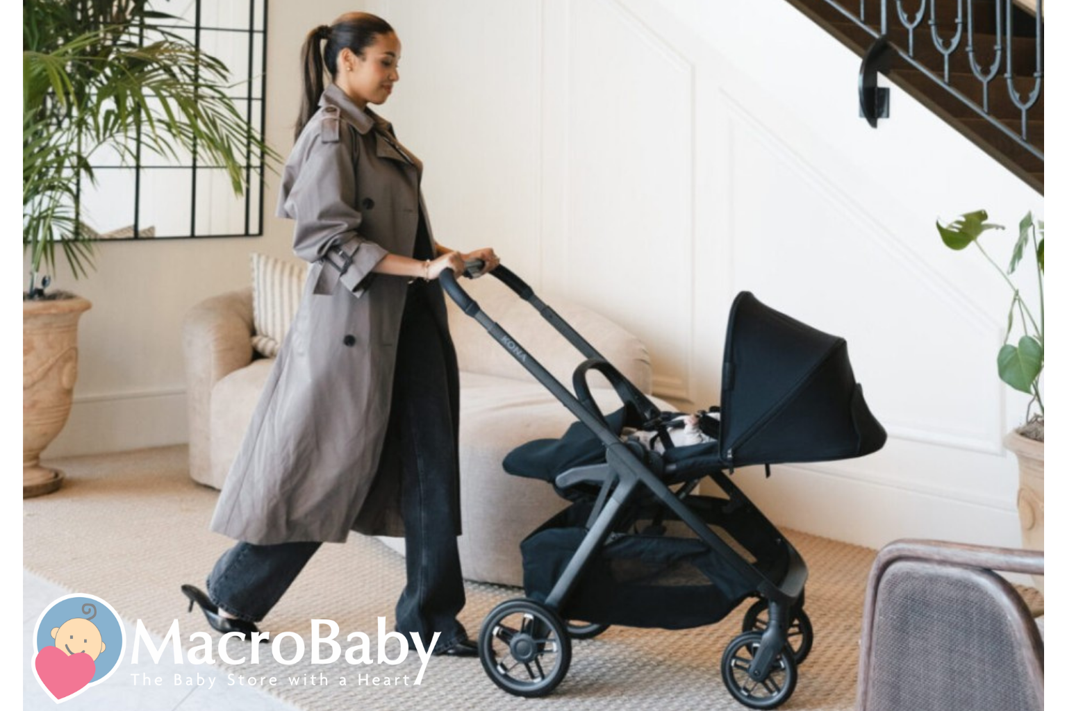 Mom pushing black Kona stroller with baby inside, modern home setting, baby gear essentials