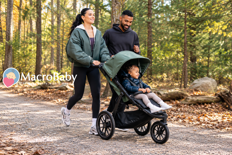 Family enjoying a walk in the forest with their toddler in a jogging stroller.