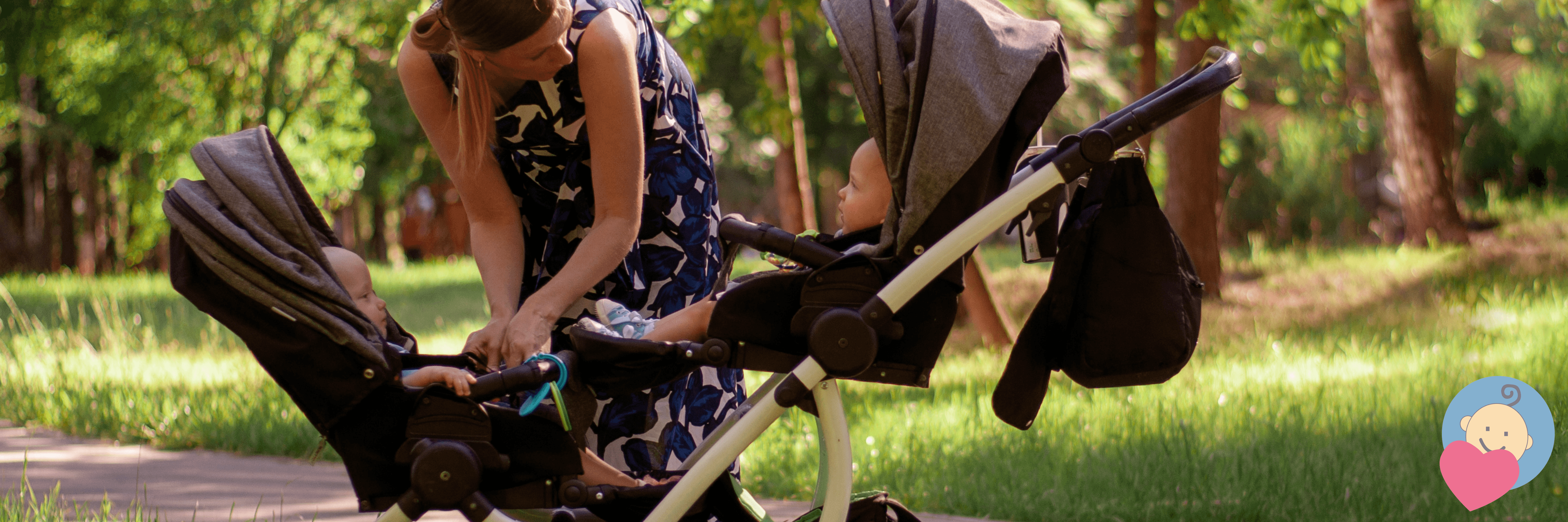 Mom adjusting twin baby strollers in a sunny park with green grass and trees