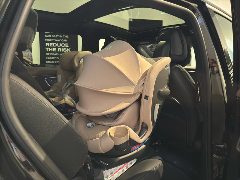 Beige baby car seat installed in vehicle with canopy and cup holders for safe travel