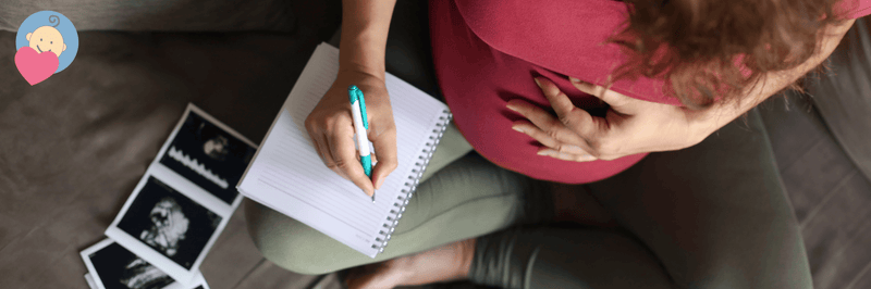 Pregnant woman writing in notebook with ultrasound photos, preparing for baby arrival