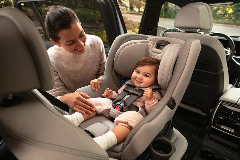 Mom securing baby in Nuna car seat inside vehicle, safe infant travel gear