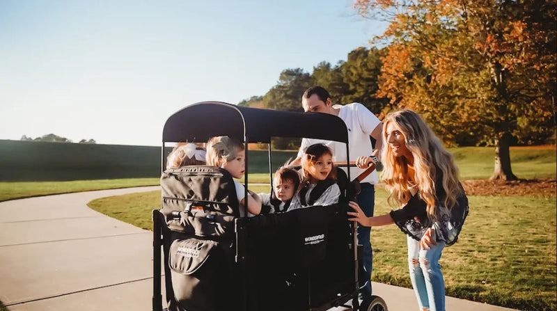 Family enjoying a walk with kids in a Wonderfold multi-child stroller outdoors