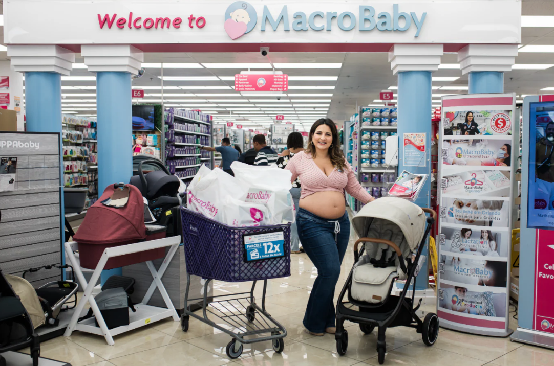 Pregnant woman shopping for baby gear with stroller and cart at MacroBaby store