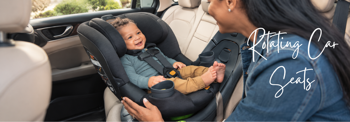 A baby sitting in a black rotating car seat inside a vehicle with a woman nearby.