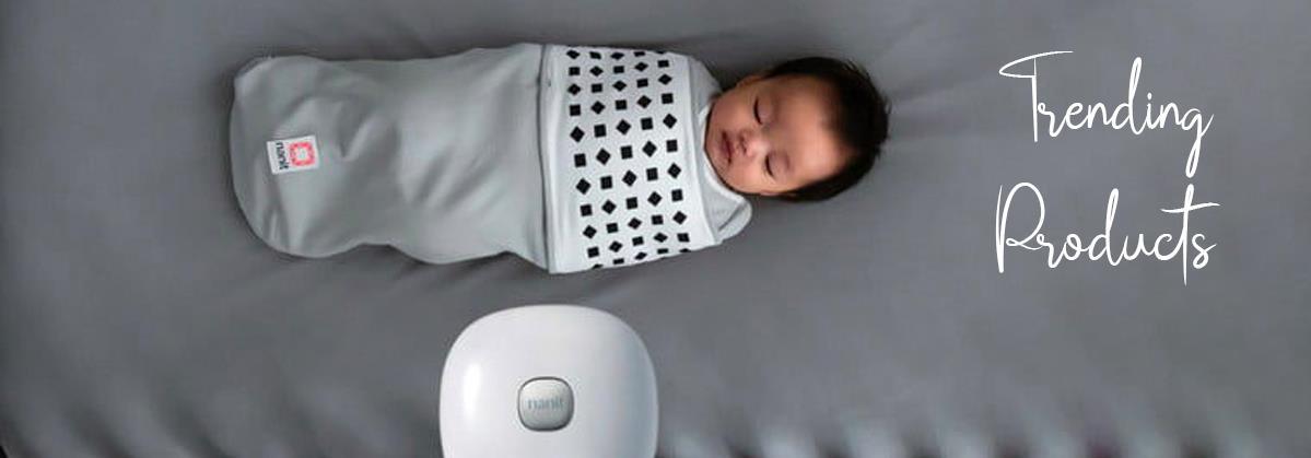 Baby sleeping in gray swaddle with black diamond pattern, white baby monitor nearby, trending products