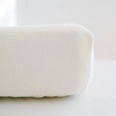 Close-up of a white Design Dua waterproof cotton muslin crib sheet.