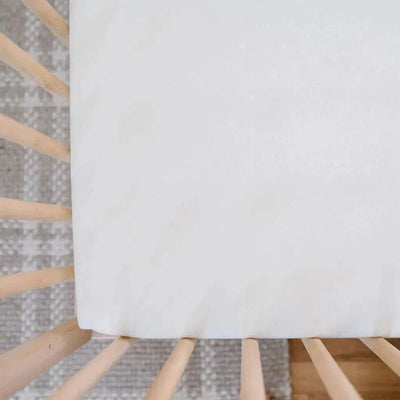 Design Dua Waterproof Cotton Crib Sheet in Pearl color on a wooden crib