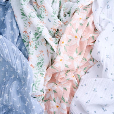 Four muslin swaddle blankets in pastel colors featuring floral and butterfly patterns, designed for infants.