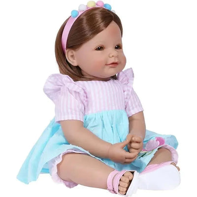Adora Toddlertime Doll in a pink and blue dress, featuring a bow headband and sitting with hands clasped.