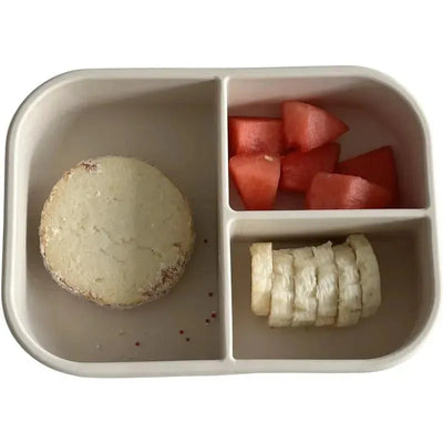 Leakproof silicone bento box in coco color, featuring compartments with watermelon, sliced banana, and a round food item.