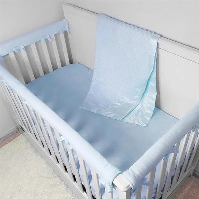 Light blue chenille minky dot receiving blanket draped over the side of a white crib with a matching blue sheet.