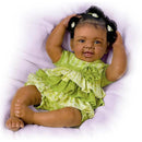 Alexis Baby Doll from Ashton Drake, featuring a smiling baby with curly hair in a green ruffled dress.