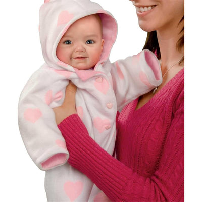 Savana Baby Doll by Ashton Drake, held by a woman, wearing a heart-patterned outfit and smiling.