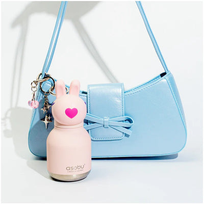 Stainless steel mini bottle with a silicone bunny head and heart, alongside a blue handbag.