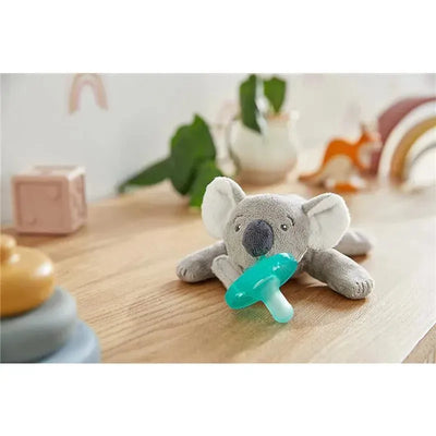 Avent Soothie Snuggle Pacifier in koala design, featuring a green pacifier held by a soft gray koala toy on a wooden surface.