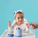 Smiling baby in a high chair enjoys food from a blue B.box Friendly Fox insulated food jar with a spoon.
