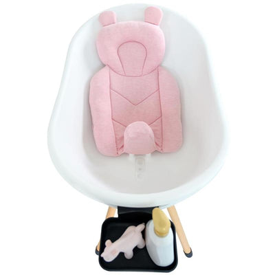 Bath support pillow in petal pink, shaped like a bear, positioned in a white baby bathtub with accessories nearby.