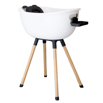 Luxury baby bathtub in white with a wooden stand, featuring a black support cushion and a side storage compartment.