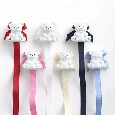 Universal pacifier holders in navy and pastel colors featuring teddy bear designs with ribbons.