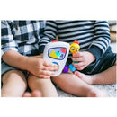 Two children are sitting on a carpet, one holding a Baby Einstein Take Along Tunes Musical Toy with buttons and colorful designs, while the other child plays with a yellow chick toy.