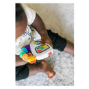 A child holds the Baby Einstein Take Along Tunes Musical Toy, featuring colorful buttons and lights, while sitting on a soft surface.