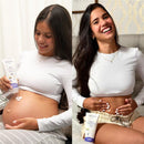Mom gently applies Baby Jolie stretch mark cream on her pregnant belly, smiling, holding the tube in a cozy setting.