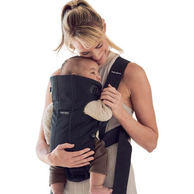 A woman holds a baby in the Babybjorn Baby Carrier Mini 3D Mesh in black, showcasing comfort and convenience.