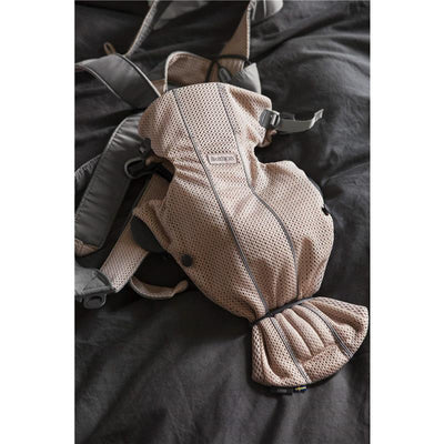 BabyBjörn Baby Carrier Mini in 3D mesh, Pearly Pink, displayed on a dark surface, highlighting its breathable fabric and adjustable straps.