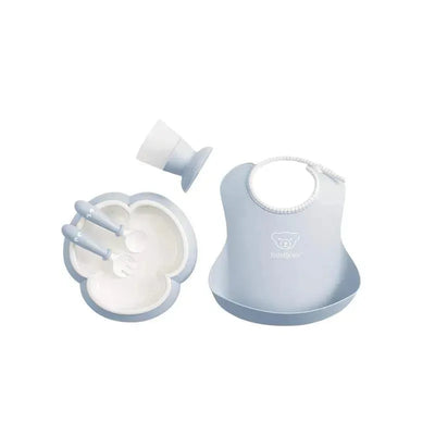 BabyBjorn powder blue baby dinner set including a bib, bowl, cup, spoon, and fork.