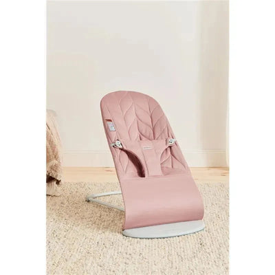 Babybjorn Bouncer Bliss in Dusty Pink, featuring a woven petal quilt design and a sturdy frame, positioned on a soft rug.
