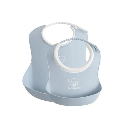 Two Babybjorn feeding bibs in powder blue, featuring a bear logo and a soft neck ring for comfortable wear.