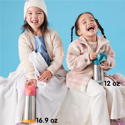 Two girls sit on a blanket, laughing. The left girl holds a 16.9 oz blush pink BBox insulated water bottle, while the right holds a 12 oz bottle.