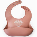 Rose pink silicone bib featuring the text, “Bless us, O Lord, and these, thy gifts...” designed for children.