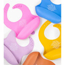Silicone bibs in various colors, including rose pink, with text featuring a blessing prayer, designed for mealtime use.