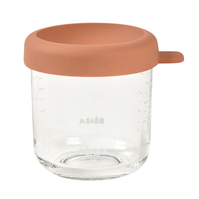 Glass baby food jar with a terracotta silicone lid, featuring measurement markings on the side.