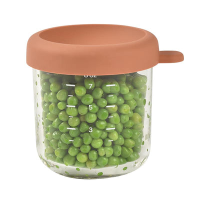 Beaba 8oz glass baby food jar in terracotta, filled with green peas and marked with measurement lines.