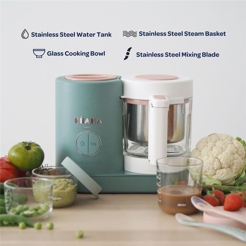 Beaba Babycook Neo, a baby food maker in cotton candy color, features a glass bowl and stainless steel components, with fresh vegetables nearby.