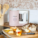 Beaba Babycook Neo Baby Food Maker in cotton candy color, designed for steaming and blending baby food, displayed with sliced fruits.