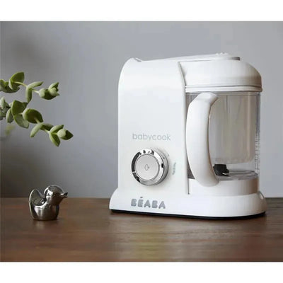 Beaba Babycook Solo 4 in 1 Baby Food Maker in white, featuring a clear bowl, control knob, and a modern design on a wooden surface.